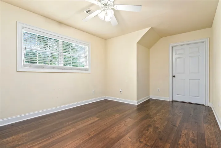 Rich hardwood flooring complements the naturally illuminated, generously sized bedroom.