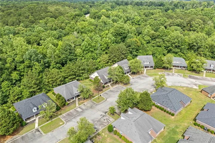 An aerial perspective reveals a serene residential community bordered by lush, verdant woodlands.
