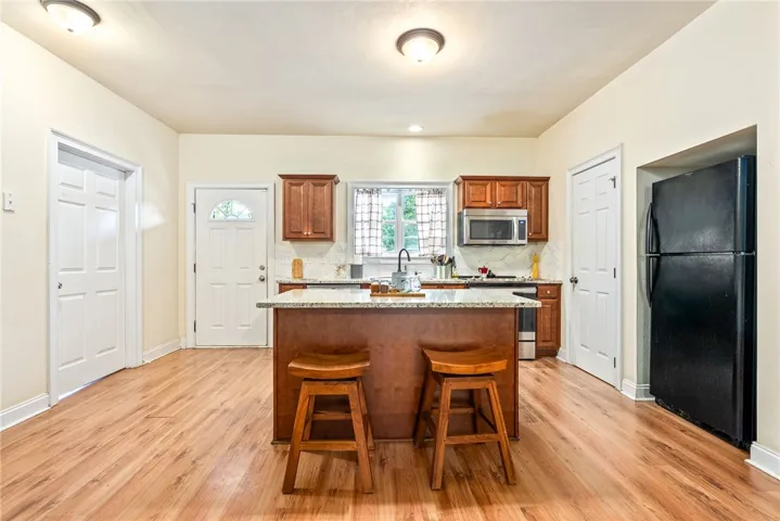 A well-appointed kitchen features a central island, granite counters, and wood flooring.