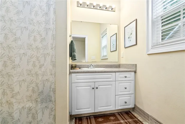 A pristine bathroom vanity, illuminated by natural light, offers ample storage and a clear mirror.
