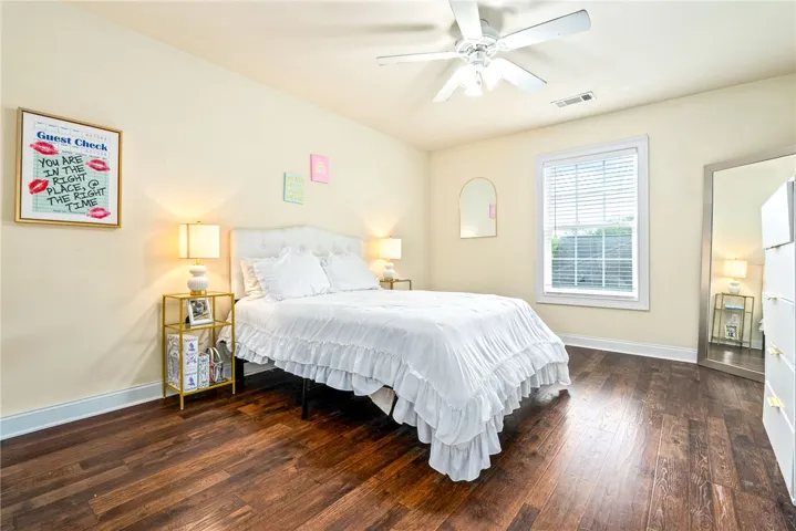Rich hardwood floors complement this naturally illuminated bedroom with a ceiling fan.