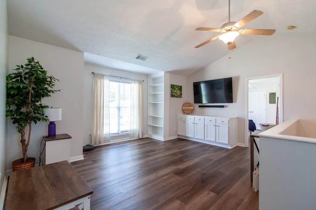 LVP flooring complements a well-lit living area/ loft featuring built-in shelving and ample natural light.
