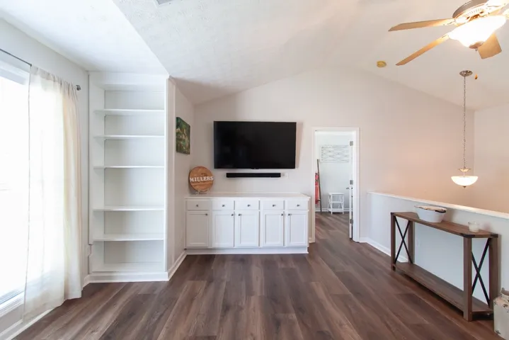 LVP flooring complements a well-lit living area/ loft featuring built-in shelving and ample natural light.