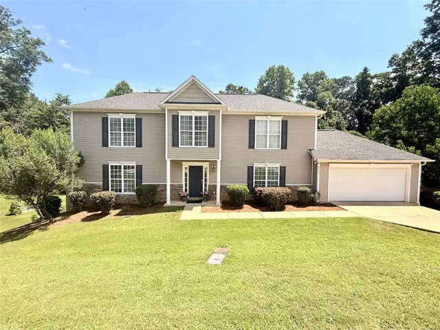 A classic two-story residence presents with tidy landscaping and a spacious attached garage.