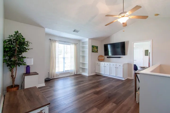 LVP flooring complements a well-lit living area/ loft featuring built-in shelving and ample natural light.