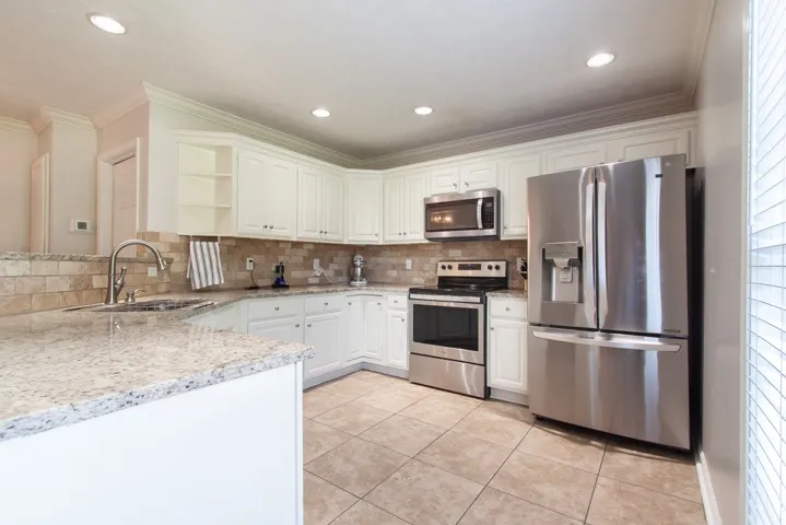 Culinary adventures await in this kitchen featuring abundant white cabinetry and pristine granite countertops.