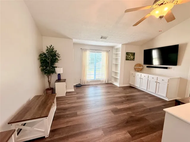 LVP flooring complements a well-lit living area/ loft featuring built-in shelving and ample natural light.