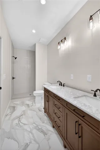 A well-lit bathroom showcases a dual-sink vanity with ample storage and a spacious walk-in shower.