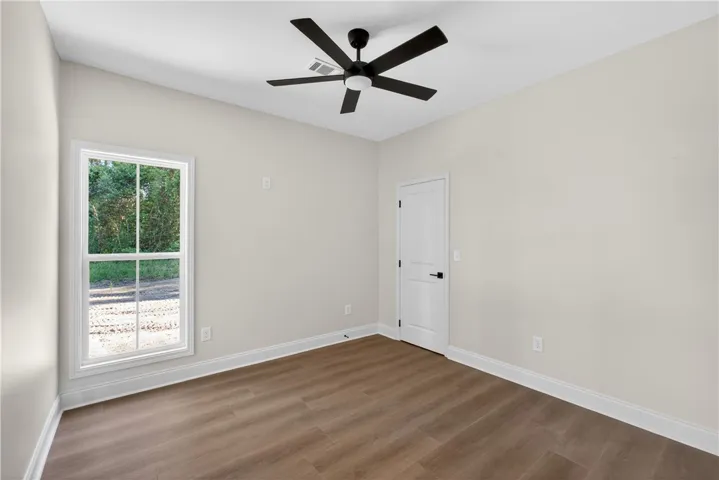 A well-lit bedroom features durable hardwood flooring and a stylish ceiling fan.