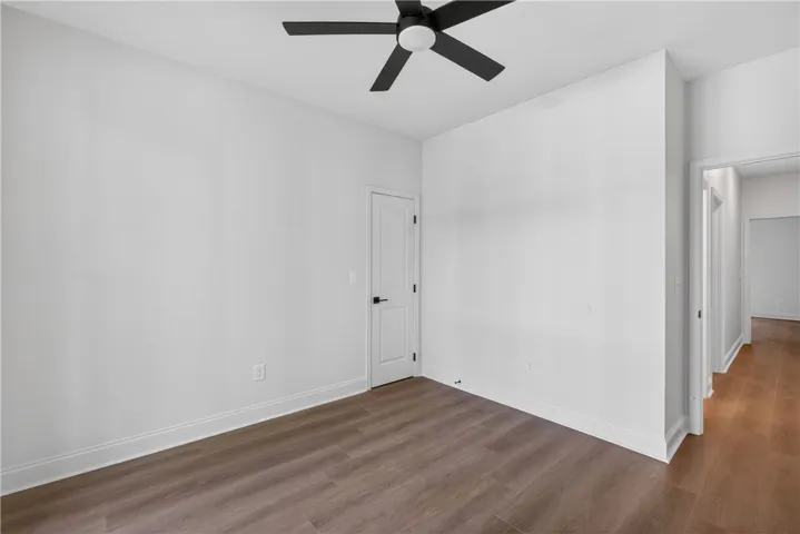 A well-lit room offers a ceiling fan for comfort and durable plank flooring.