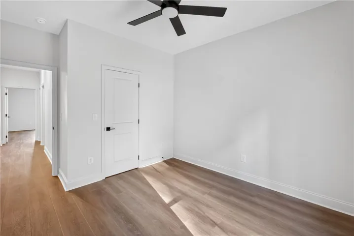 Well-lit room with modern wood flooring and a contemporary ceiling fan offers adaptable living space.