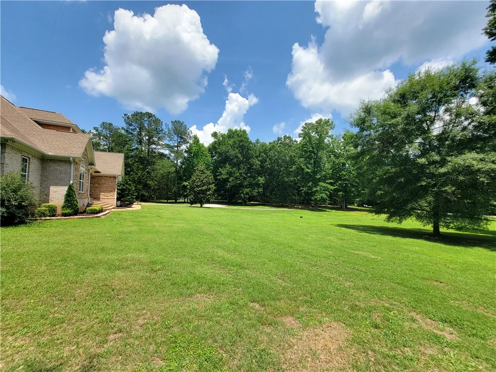 A sweeping green lawn unfolds before a brick residence, framed by a clear blue sky.
