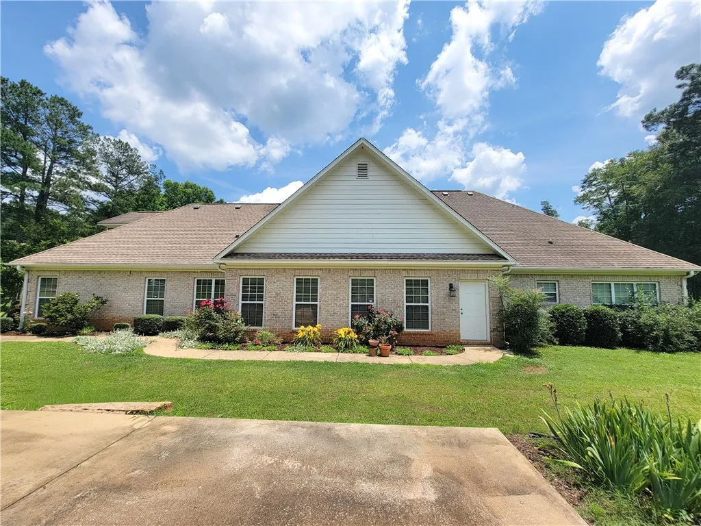 A classic brick exterior offers timeless curb appeal, surrounded by mature trees and verdant landscaping.