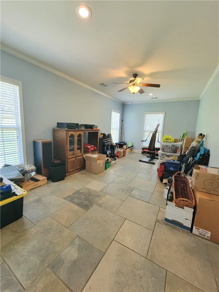 A well-lit room featuring durable tile flooring and a ceiling fan for year-round comfort.