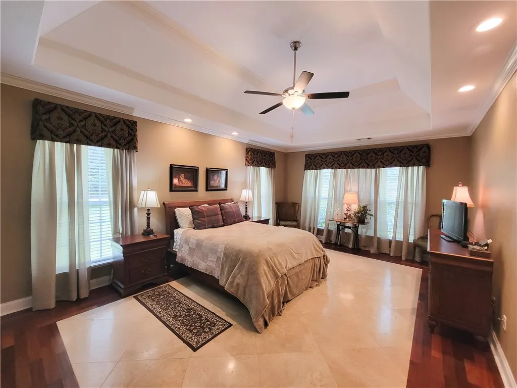 A spacious chamber with a detailed tray ceiling and mixed flooring offers abundant natural illumination.