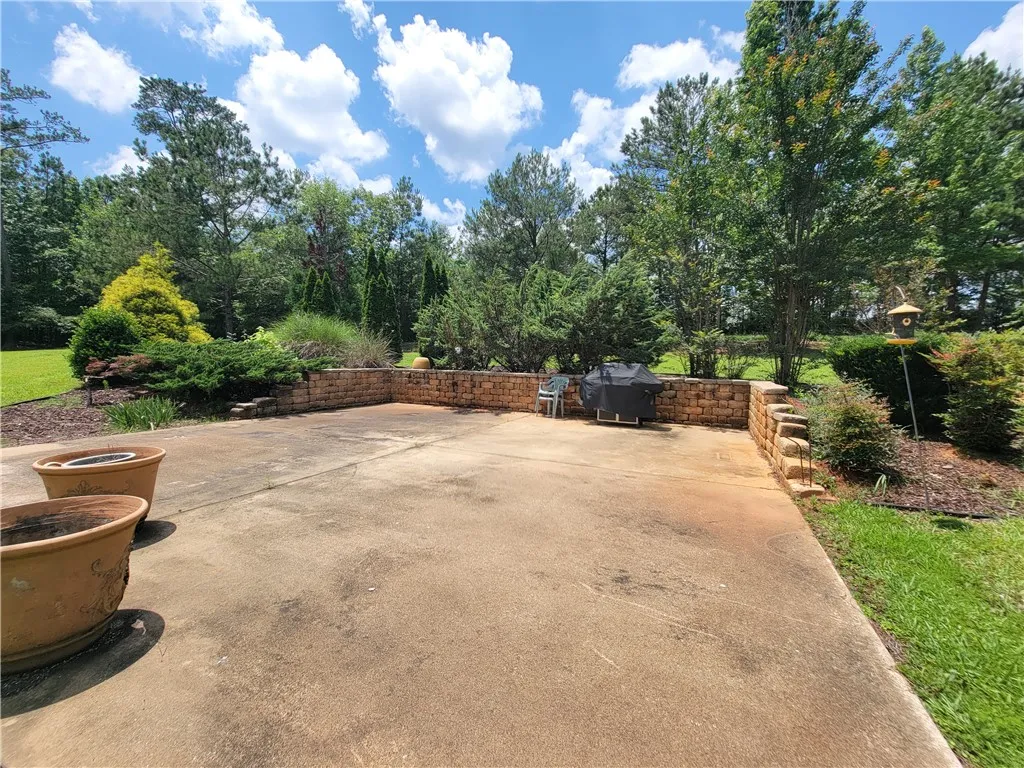 A generous concrete patio with a retaining wall and abundant natural landscaping.