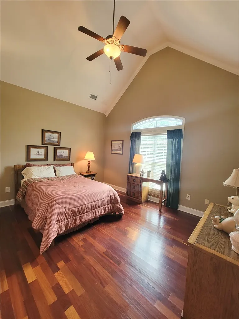 Rich hardwood floors complement the vaulted ceiling and crown molding in this sun-filled bedroom.