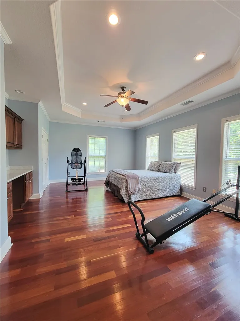 Rich hardwood floors complement tray ceilings in this generously proportioned sleeping area.