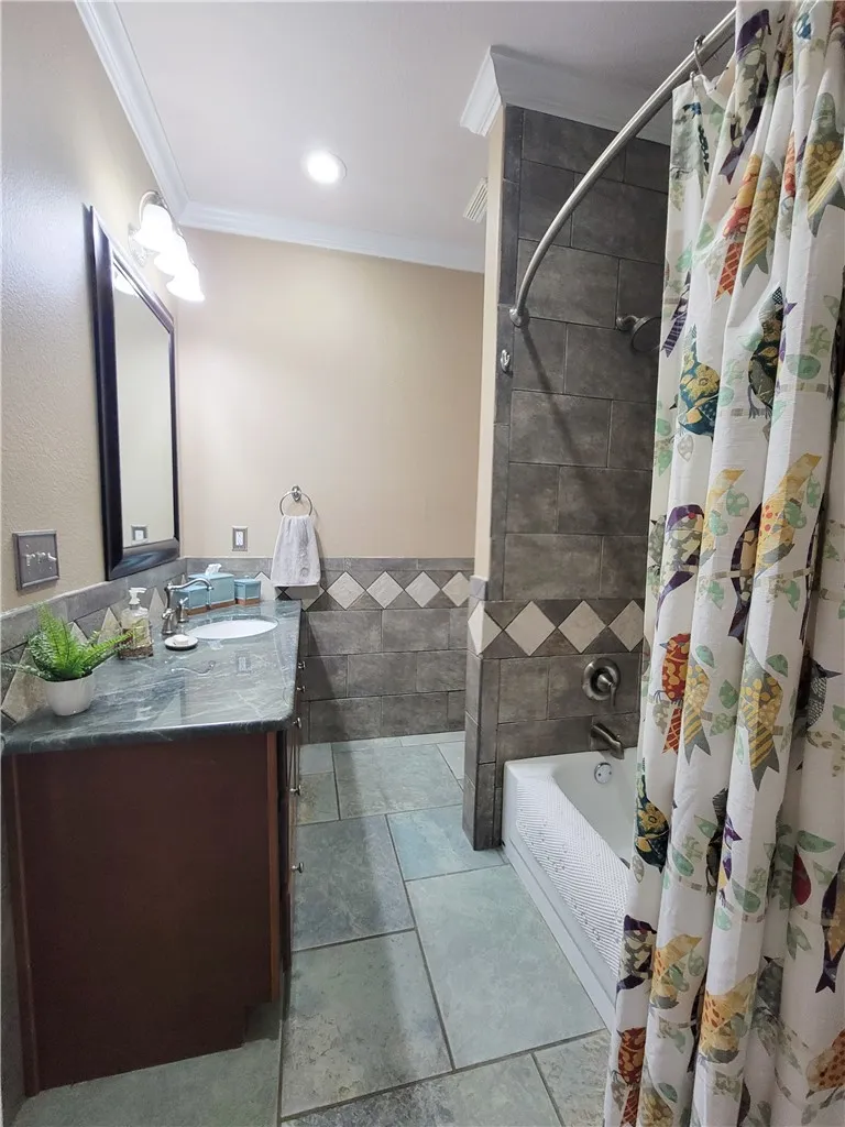 A well-appointed bath features a tiled shower and a vanity with a sleek countertop.