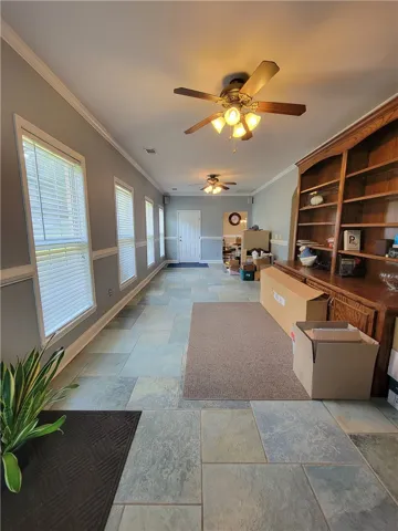 A lengthy, well-lit hallway features multiple windows and a beautiful tiled floor.