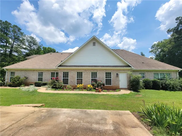 A classic brick exterior offers timeless curb appeal, surrounded by mature trees and verdant landscaping.