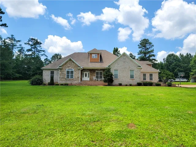 A classic brick and stone facade welcomes guests to this inviting residence, framed by mature trees and a verdant lawn.