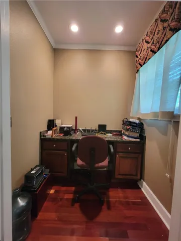 A dedicated home office space with rich wood flooring and practical built-in desk cabinetry.