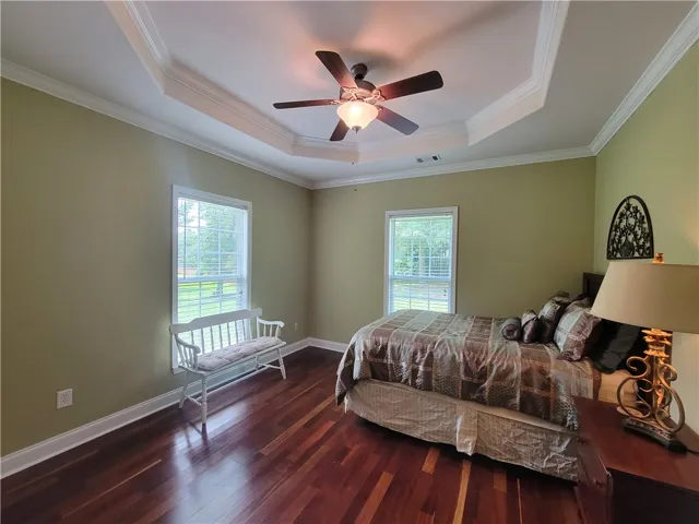 Rich hardwood floors complement the elegant tray ceiling and ample natural light in this inviting chamber.