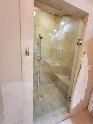 Step into a generously sized tiled shower, featuring a convenient built-in bench and glass enclosure.