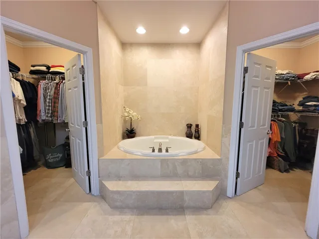 Indulge in a relaxing soak in this elegant bathtub, flanked by spacious walk-in closets.