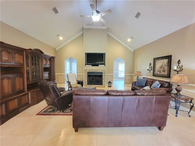 Vaulted ceilings elevate this generously proportioned living room, centered around a sophisticated fireplace.