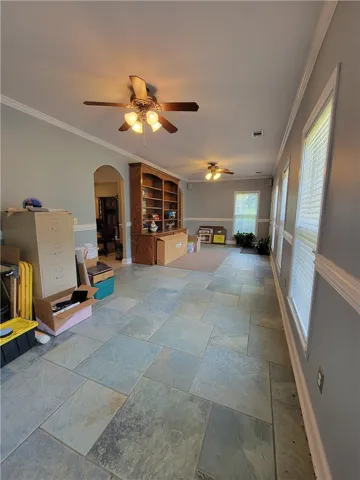 Functional family room features stone tile flooring, ample natural light, and classic ceiling fans.