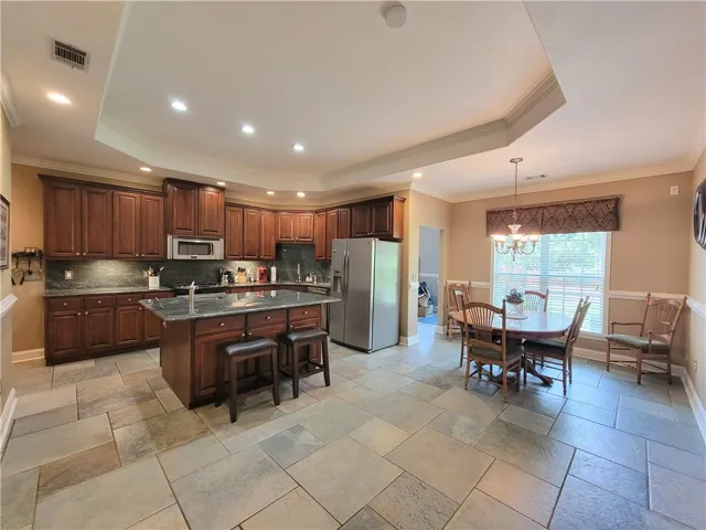 An inviting kitchen and dining area feature rich wood cabinetry, stone countertops, and durable tile flooring.