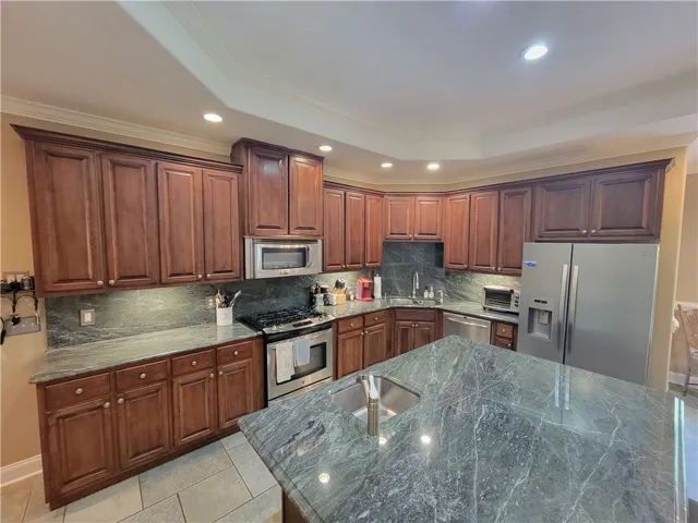 Custom cabinetry and green marble countertops create a striking kitchen space.