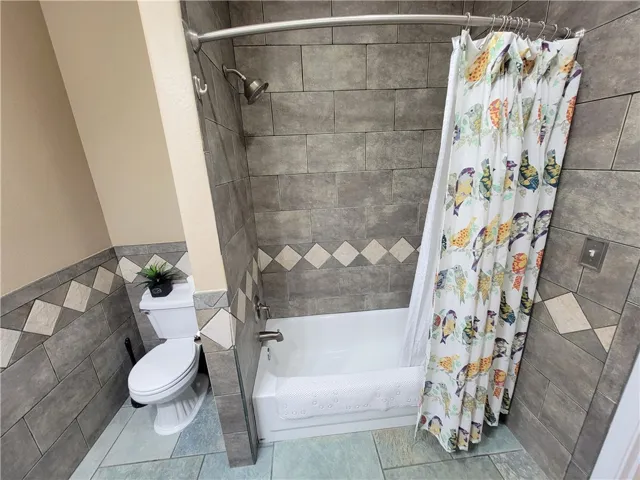 The bathroom's elegant tile work creates a sophisticated atmosphere around the bathtub and commode.