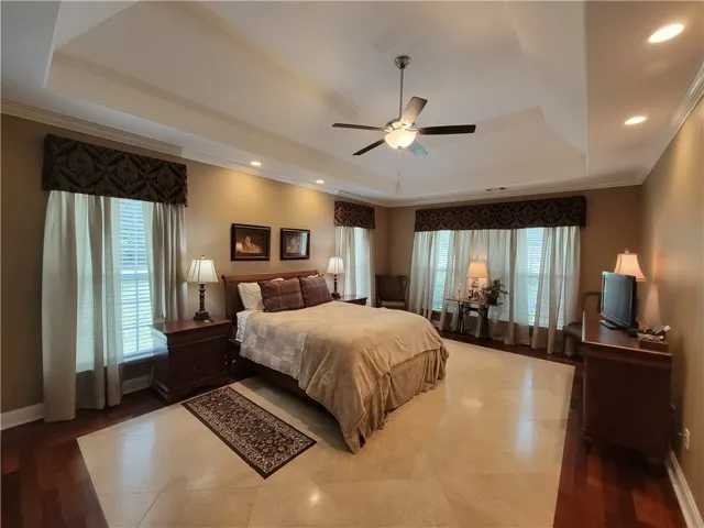 Recessed lighting and a ceiling fan illuminate this spacious primary bedroom.