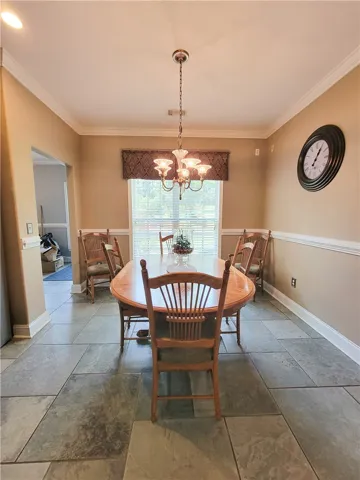 A refined dining space features crown molding, a classic chandelier, and durable stone tile flooring.