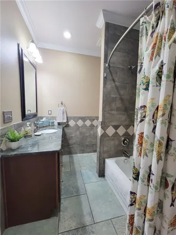 A well-appointed bath features a tiled shower and a vanity with a sleek countertop.