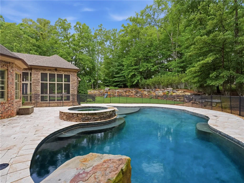 An inviting backyard oasis with a pristine pool and spa, set against a backdrop of mature trees.