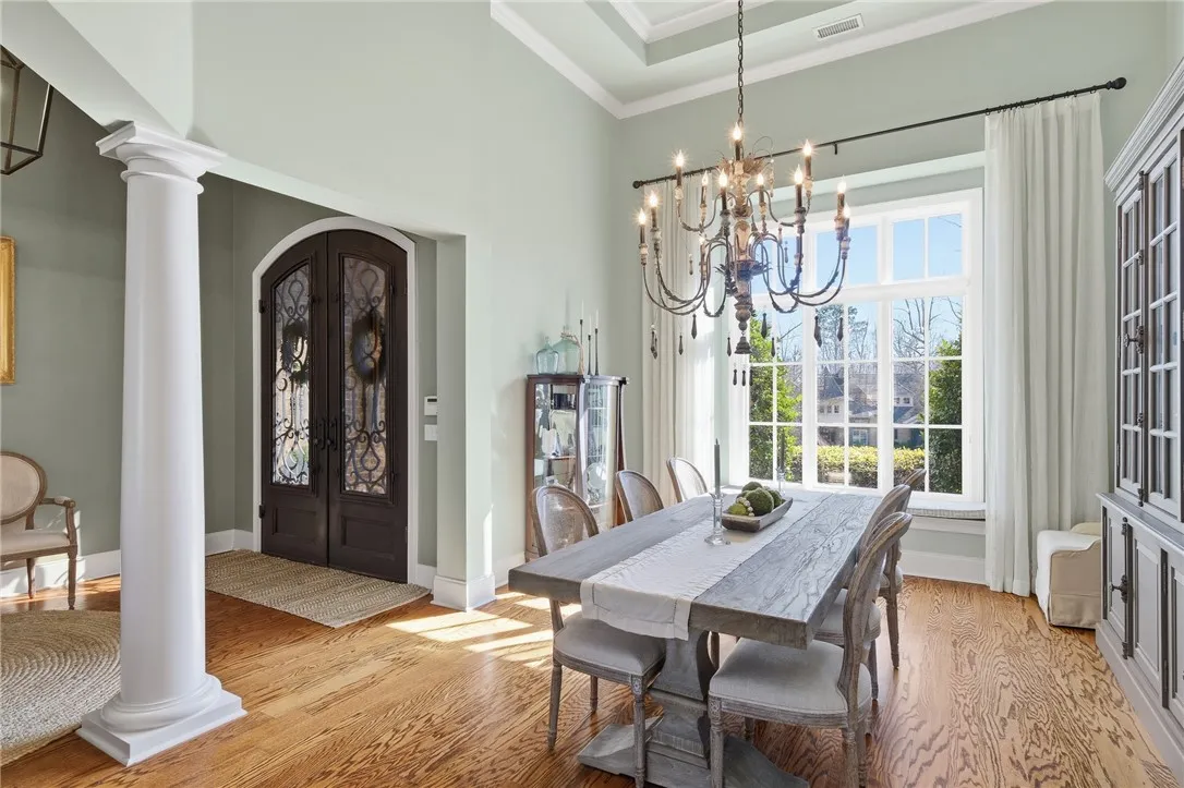 Ornate double doors welcome you into this elegant dining room featuring rich hardwood floors and an intricate chandelier.