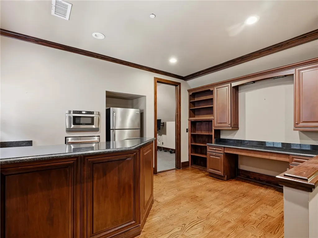 A well-appointed kitchen space offers an entertainment bar, stainless appliances, and rich wood cabinetry.