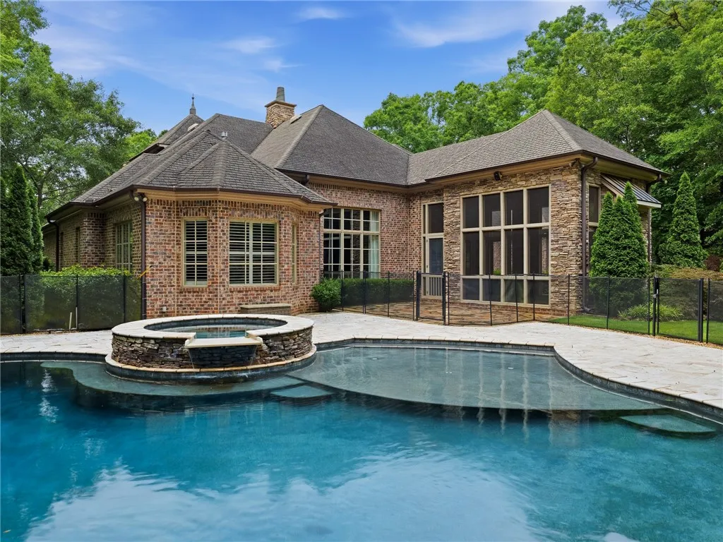 An inviting in-ground pool and stone-accented spa provide outdoor relaxation next to this stately brick residence.