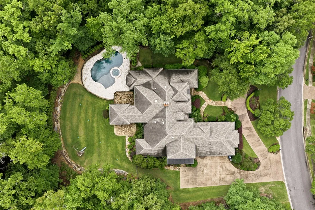 An aerial perspective reveals a luxurious estate nestled amidst a verdant landscape, showcasing an inviting pool and meticulously manicured grounds.