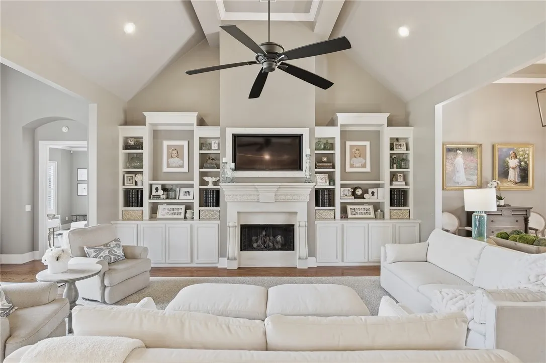 A well-lit gathering space features a vaulted ceiling and a stately fireplace with built-in shelving.
