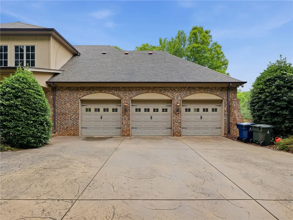 Three garage doors complement the brick and stucco exterior, offering ample vehicle storage.