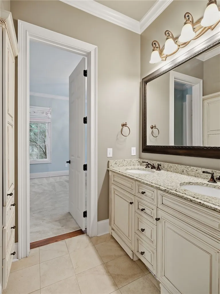 Double vanities with stone counters and decorative lighting provide a functional and refined space.