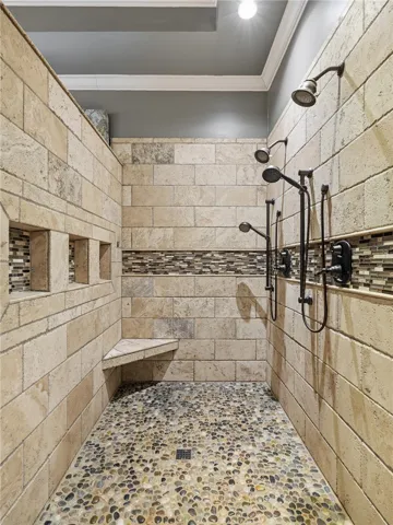 Indulge in a luxurious walk-in shower with pebble flooring and multiple showerheads.