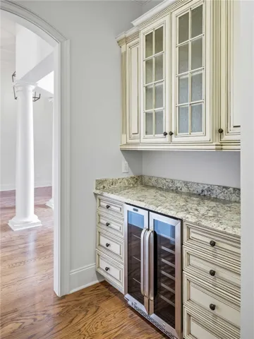 Elegant butler pantry features custom cabinetry, stone countertops, and a built-in beverage cooler.