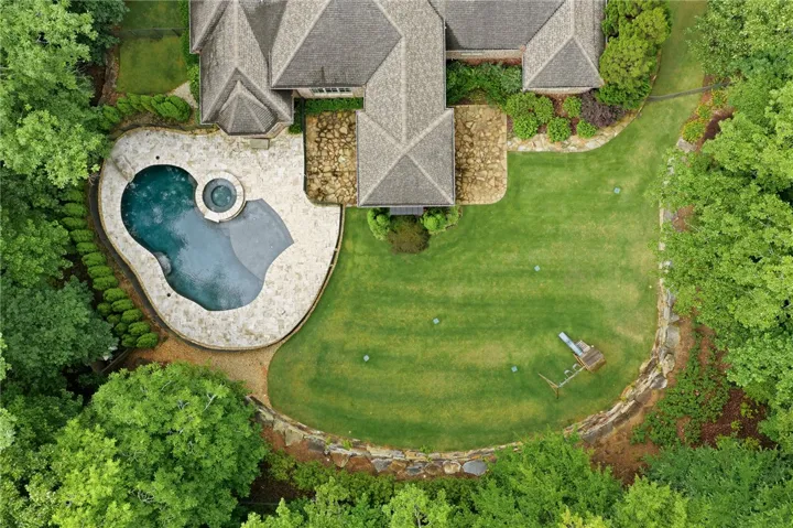 An aerial perspective reveals a private pool with an integrated spa, surrounded by lush, maintained landscaping.