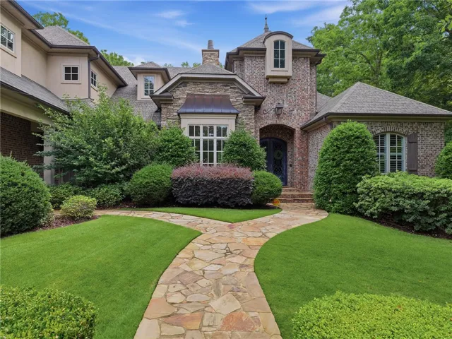 A graceful stone pathway guides you through meticulously manicured landscaping to this distinguished brick residence.
